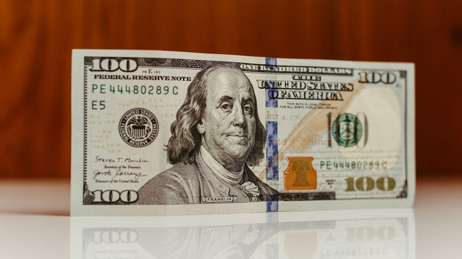 Close-up of a US one hundred dollar bill featuring Benjamin Franklin, representing national debt and federal borrowing